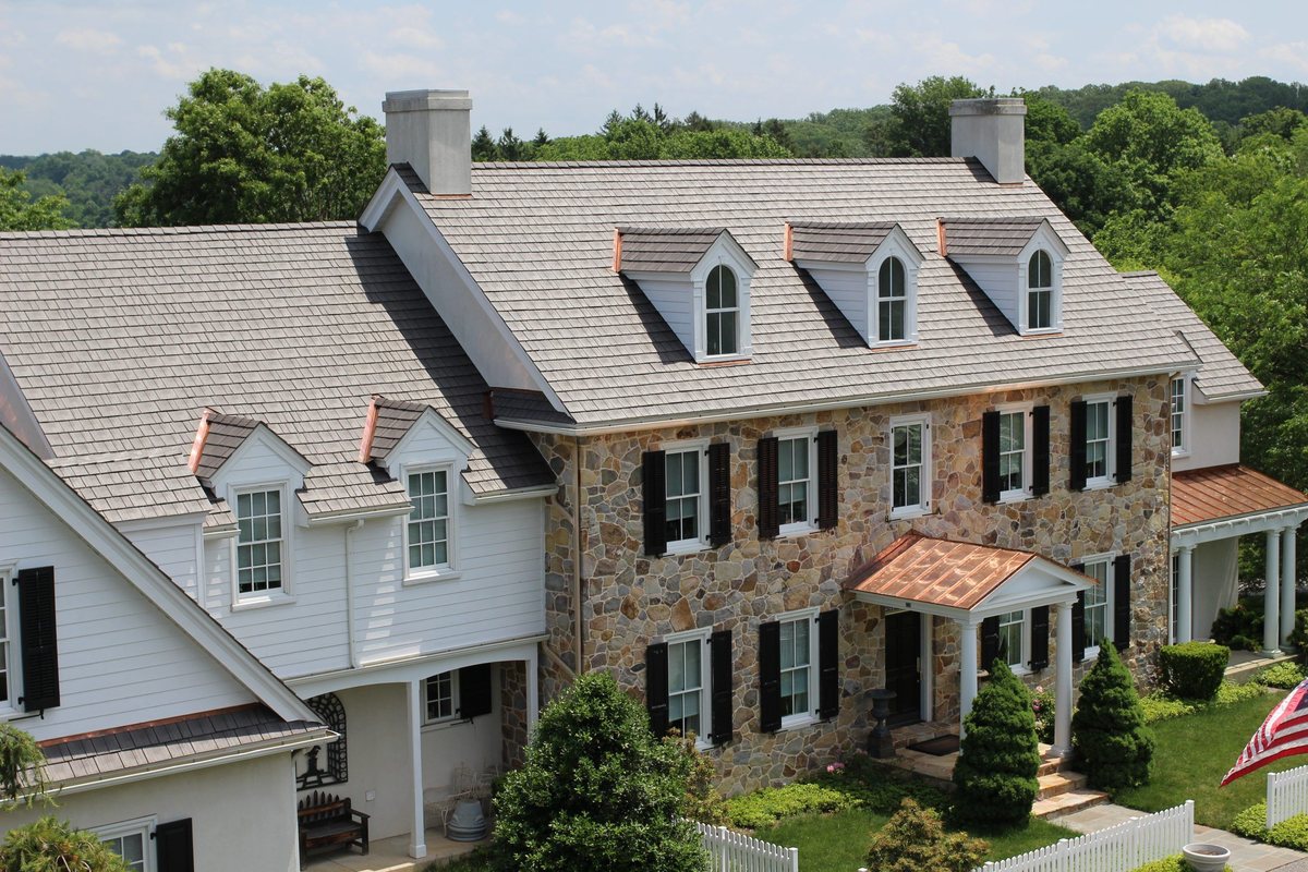 Home with a premium Enviroshake composite shake roof, copper-capped dormers and stone facade
